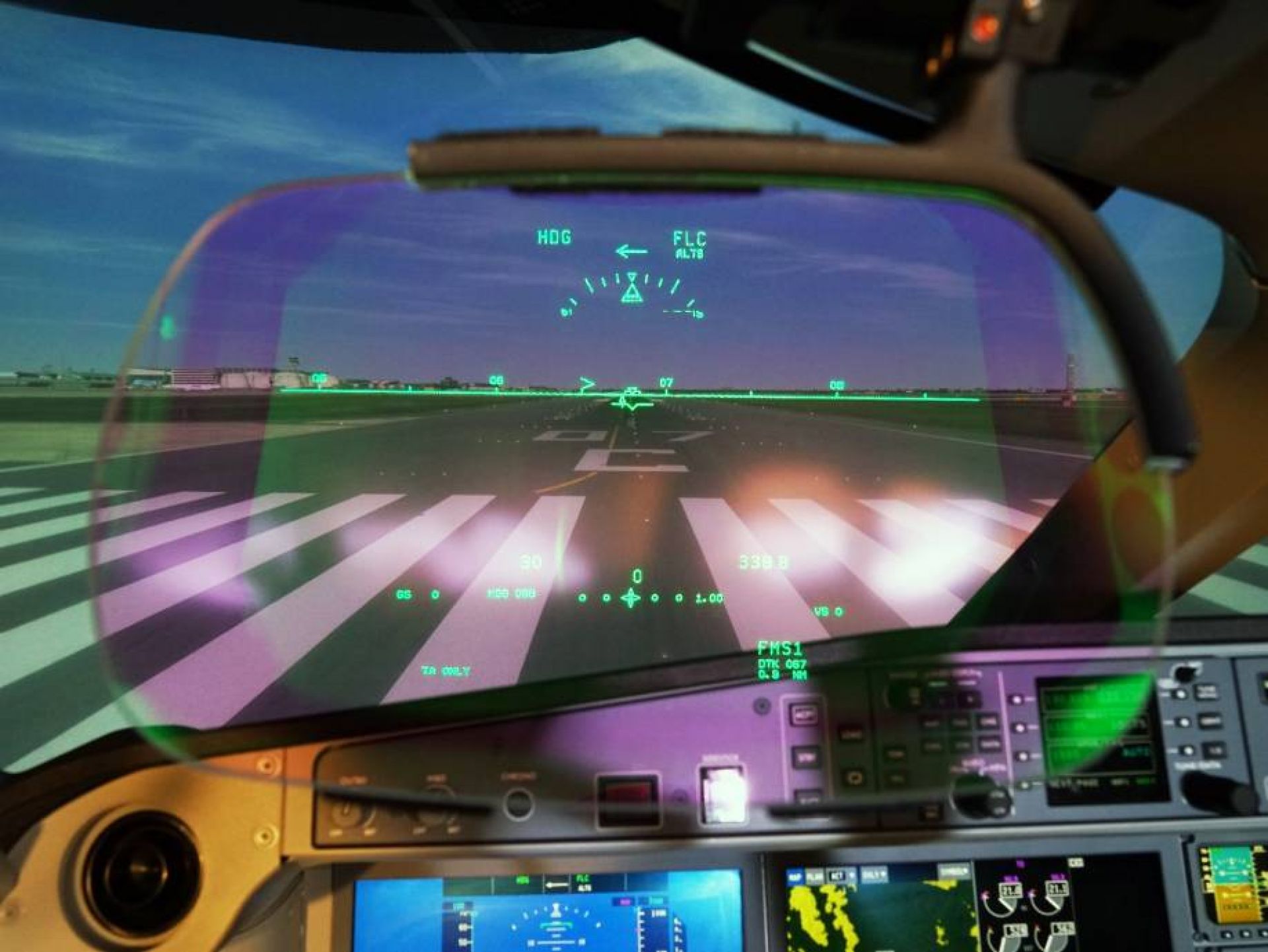 Head-up display of the Airbus A220 in front of cockpit instruments and the projected runway.